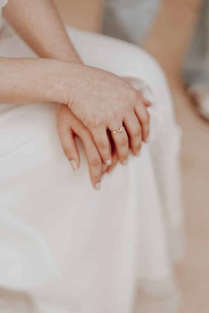Hochzeitsfotograf Niederrhein 3 Braut sitzt mit verschränkten Händen auf einem Stuhl.