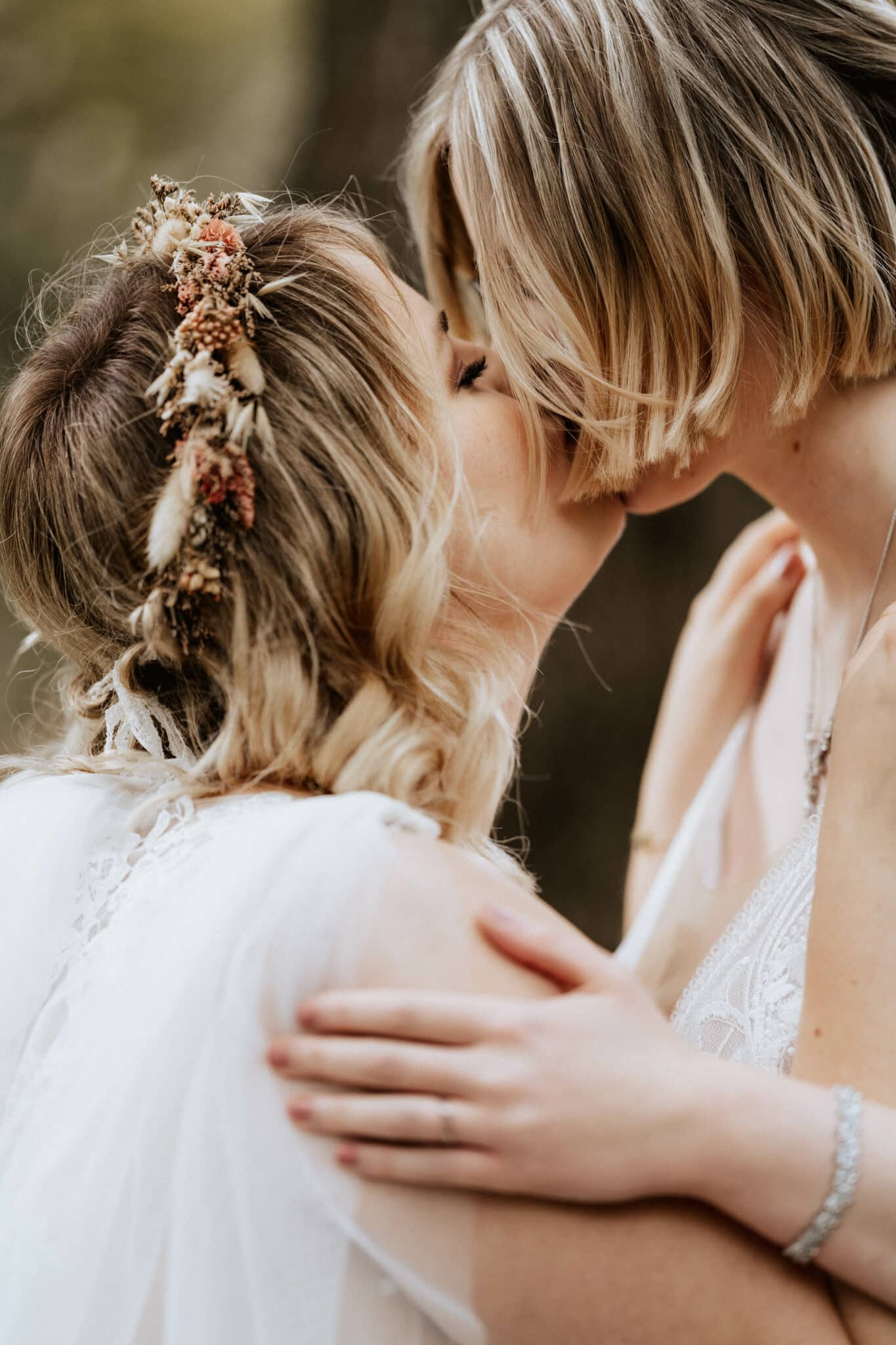 Lesbisches Hochzeitspaar küsst sich verliebt auf den Mund.