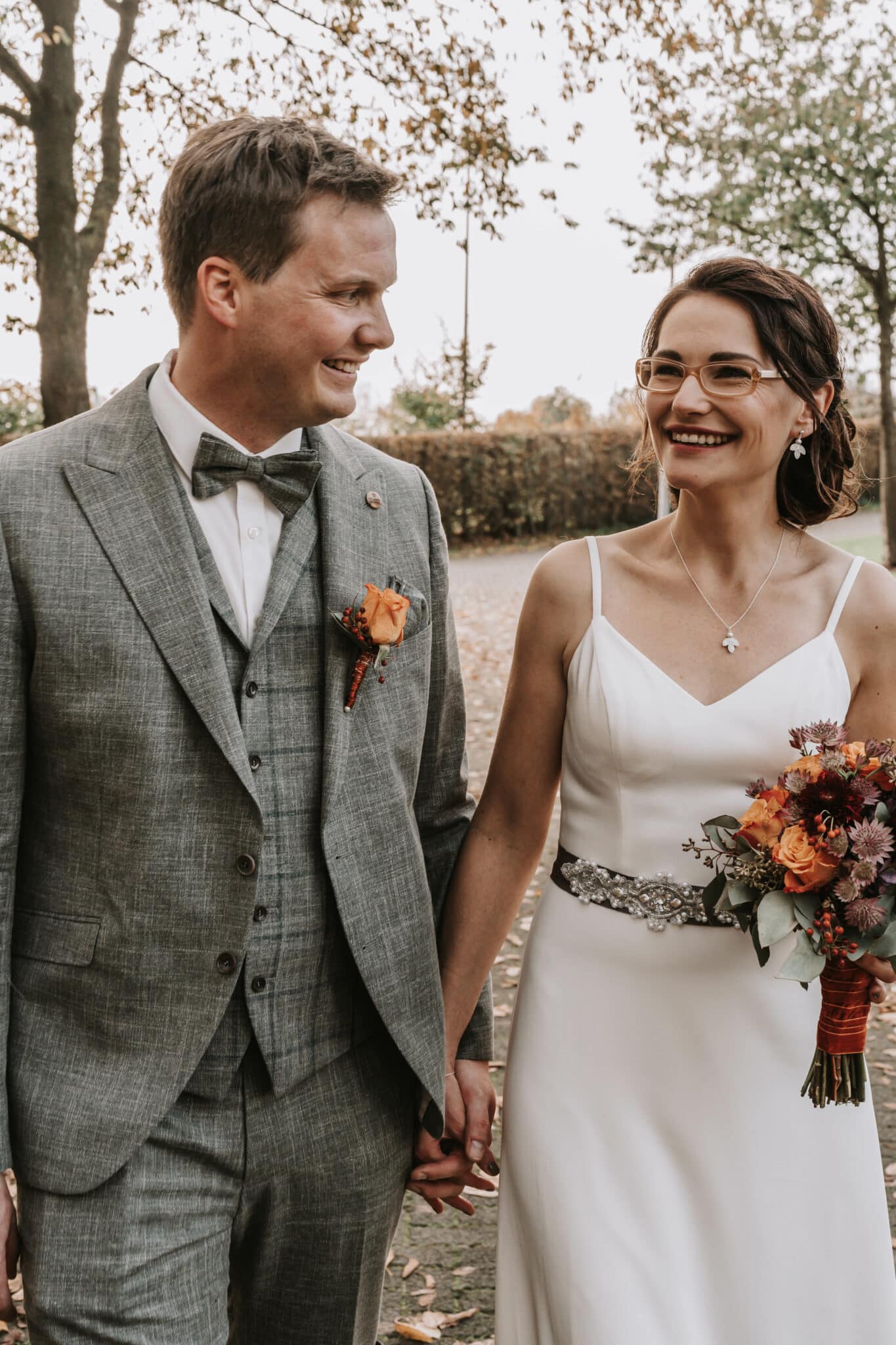 Hochzeitspaar läuft Hand in Hand und guckt sich dabei verliebt an.