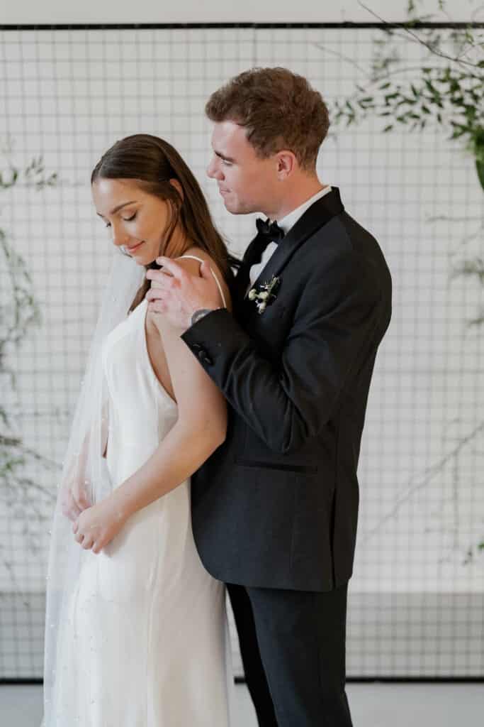 Hochzeitsfotograf NRW 3 Bräutigam steht hinter seiner Braut und berührt zärtlich ihre Schultern.